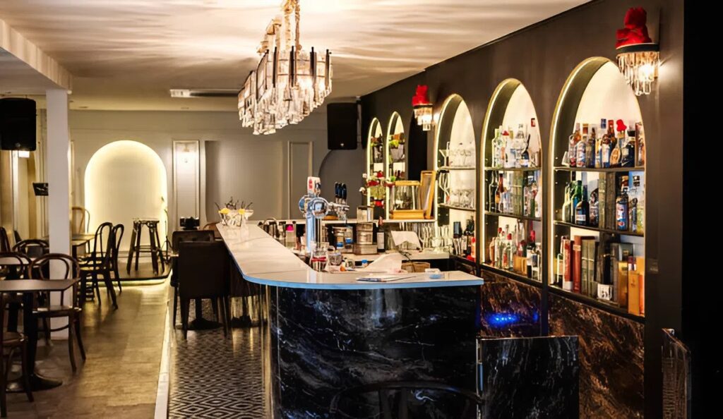 Elegant restaurant bar makeover by interior painter in Broadmoor, CO, with dark walls, marble counter, and backlit bottle display