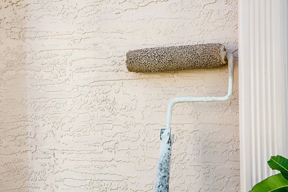 Stucco wall being painted with a paint roller by a house painter in Manitou, CO