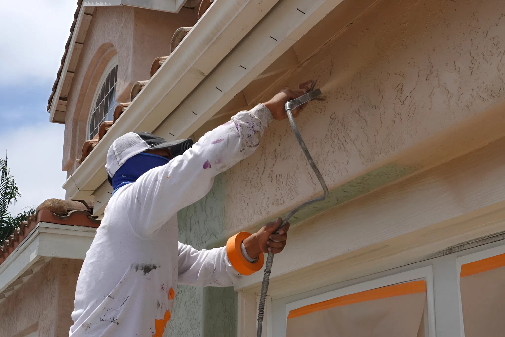 A professional applying coating over repaired stucco to ensure a smooth and even texture by an interior painter in Broadmoor, CO